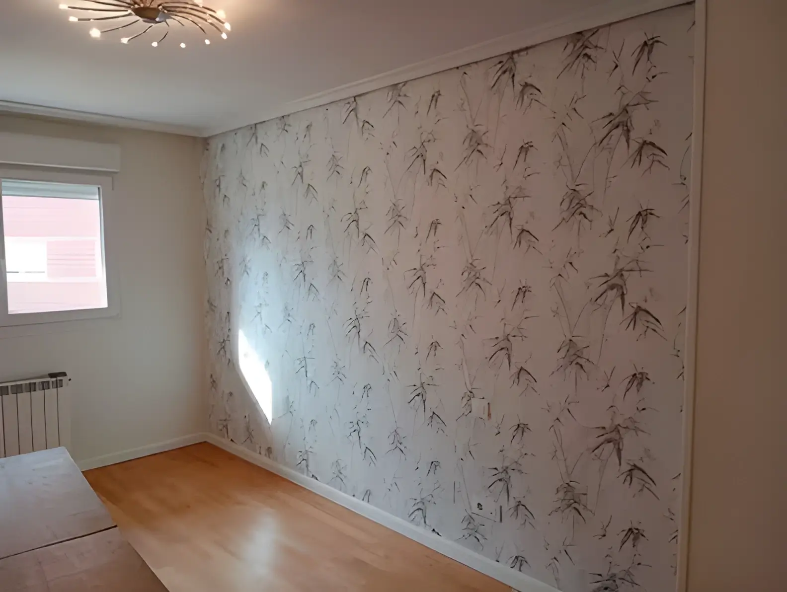 Los Pintores Castellón colocando papel pintado en pared de acento de habitación luminosa