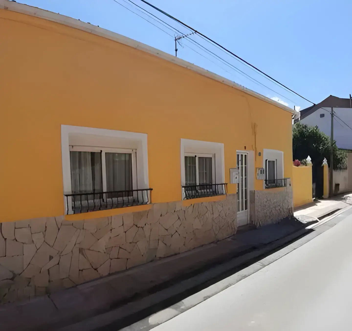 Los Pintores Castellón Fachada de casa tradicional pintada en color amarillo con zócalo de piedra